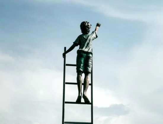 Mensch auf einer Leiter greift zum Himmel